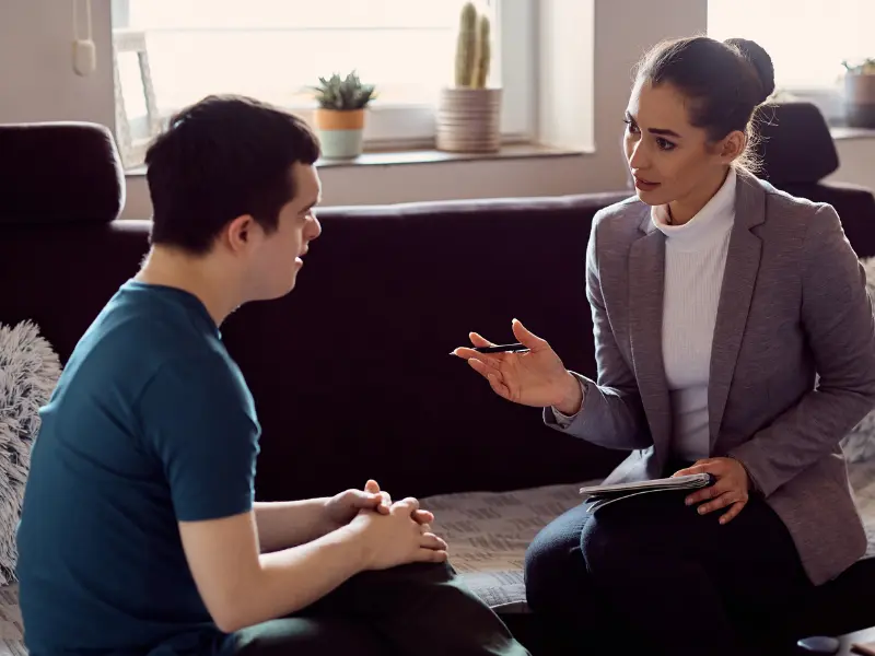 Disabled man sitting on couch talking with support coordinator