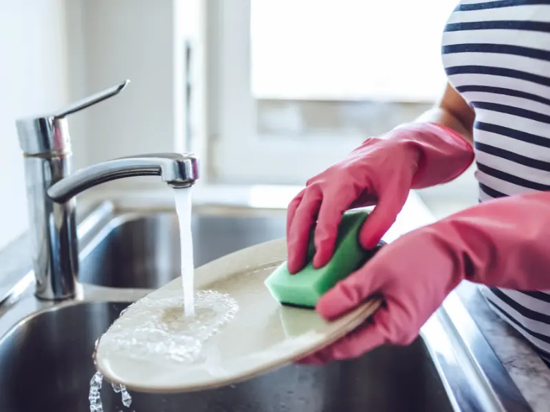 Close up of person doing the dishes in kitchen sink