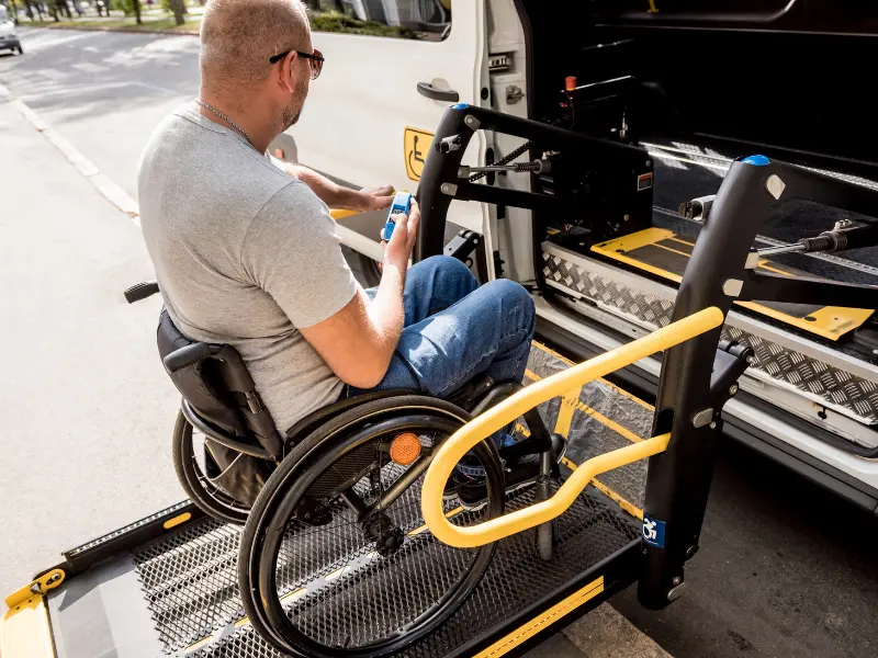 Disabled man in wheelchair getting into disability van via lift