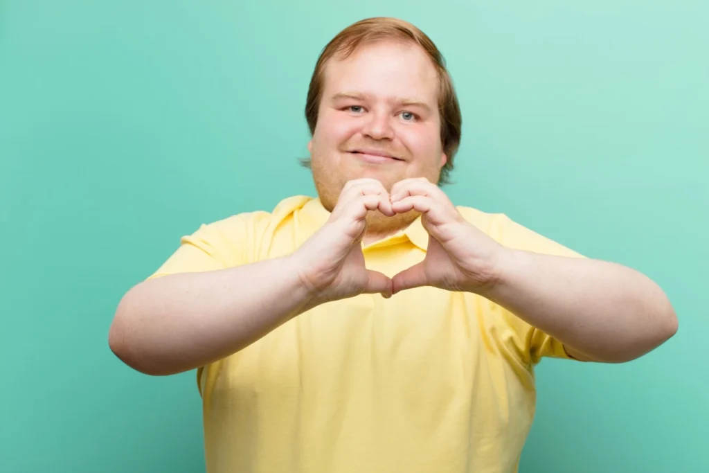 Disabled man making shape of love heart with hands toward the camera