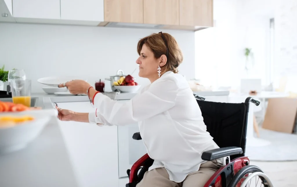Disabled woman at home in wheelchair putting dishes away